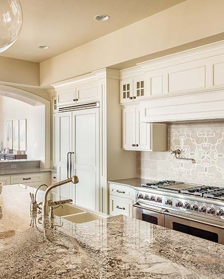 A kitchen with white cabinets , granite counter tops , a stove and a sink.