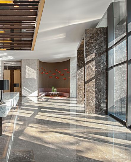 A large lobby with a lot of windows and marble floors.