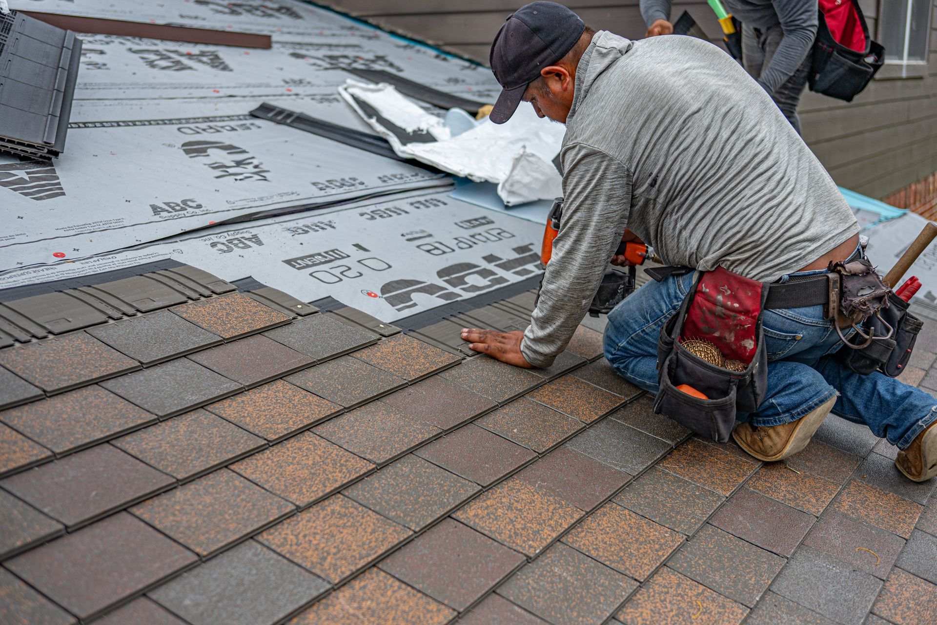 Roofer installing new asphalt shingles during a roof replacement