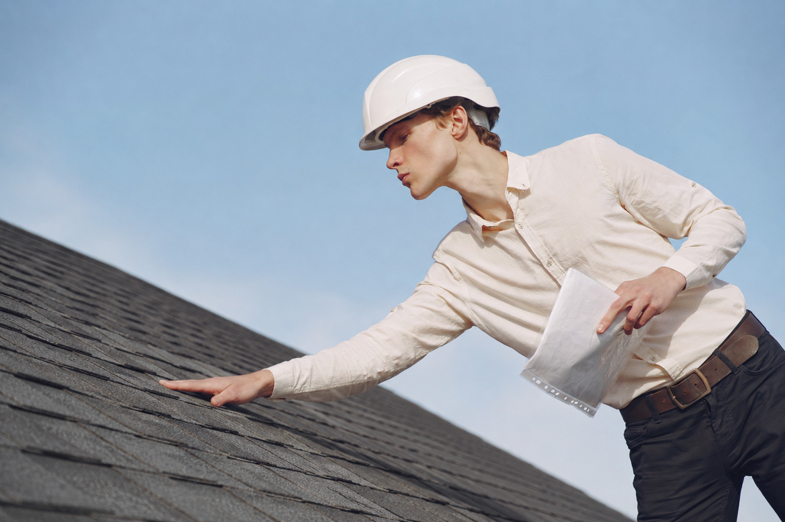 Roof inspector checking asphalt shingles for visible wear