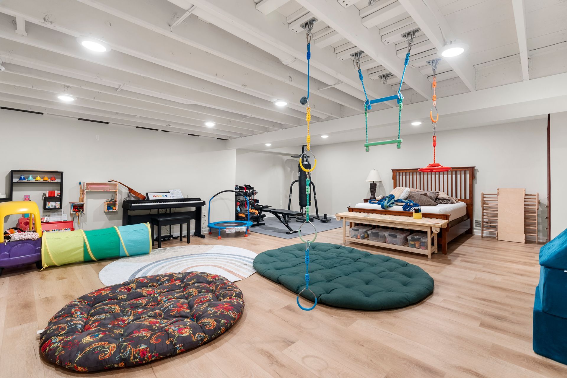 A large room with a bed , piano , and a lot of toys.