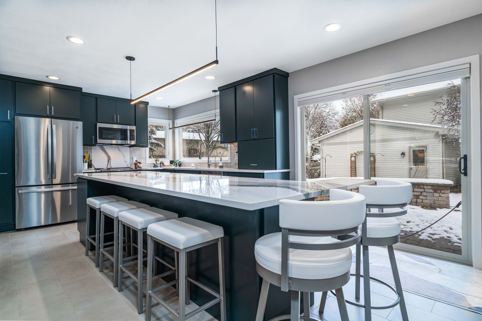 A kitchen with stainless steel appliances and a large island with stools.