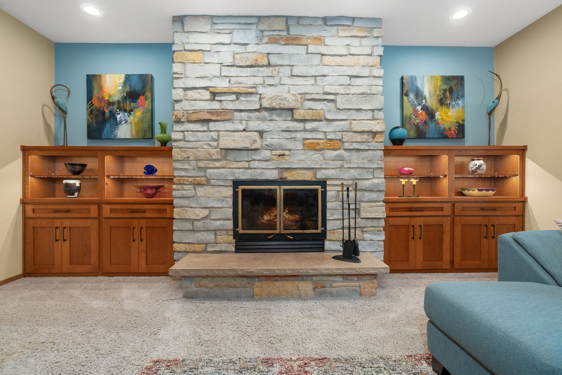 A living room with a stone fireplace and a blue couch