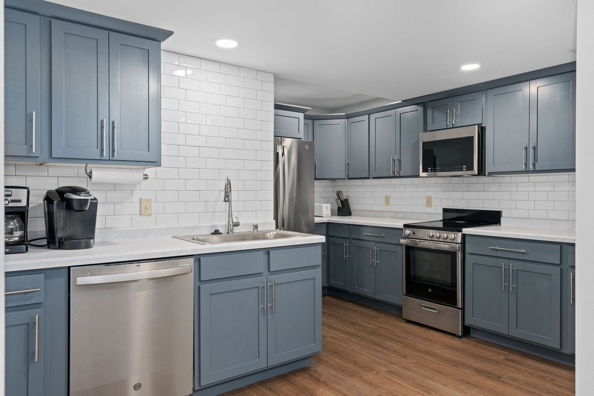 A kitchen with blue cabinets and stainless steel appliances.