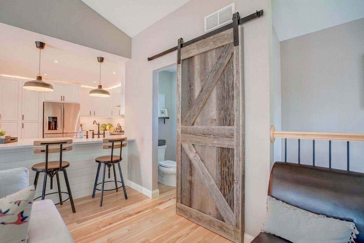 A living room with a sliding barn door leading to a kitchen.