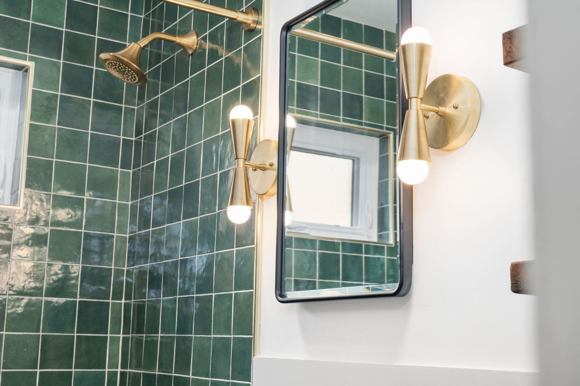 A bathroom with green tiles and a mirror.