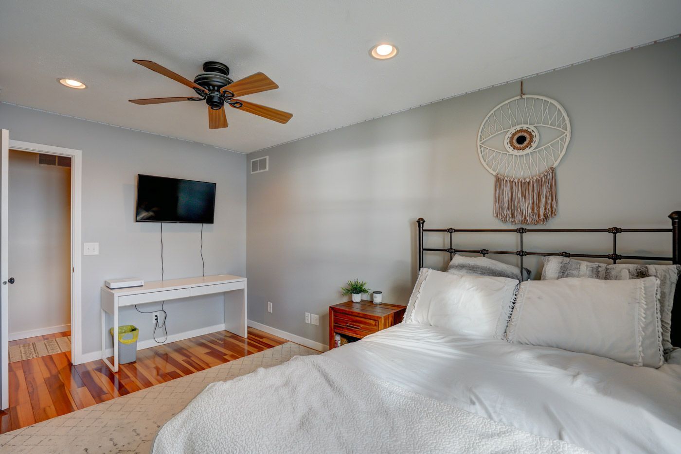A bedroom with a bed , desk , television and ceiling fan.
