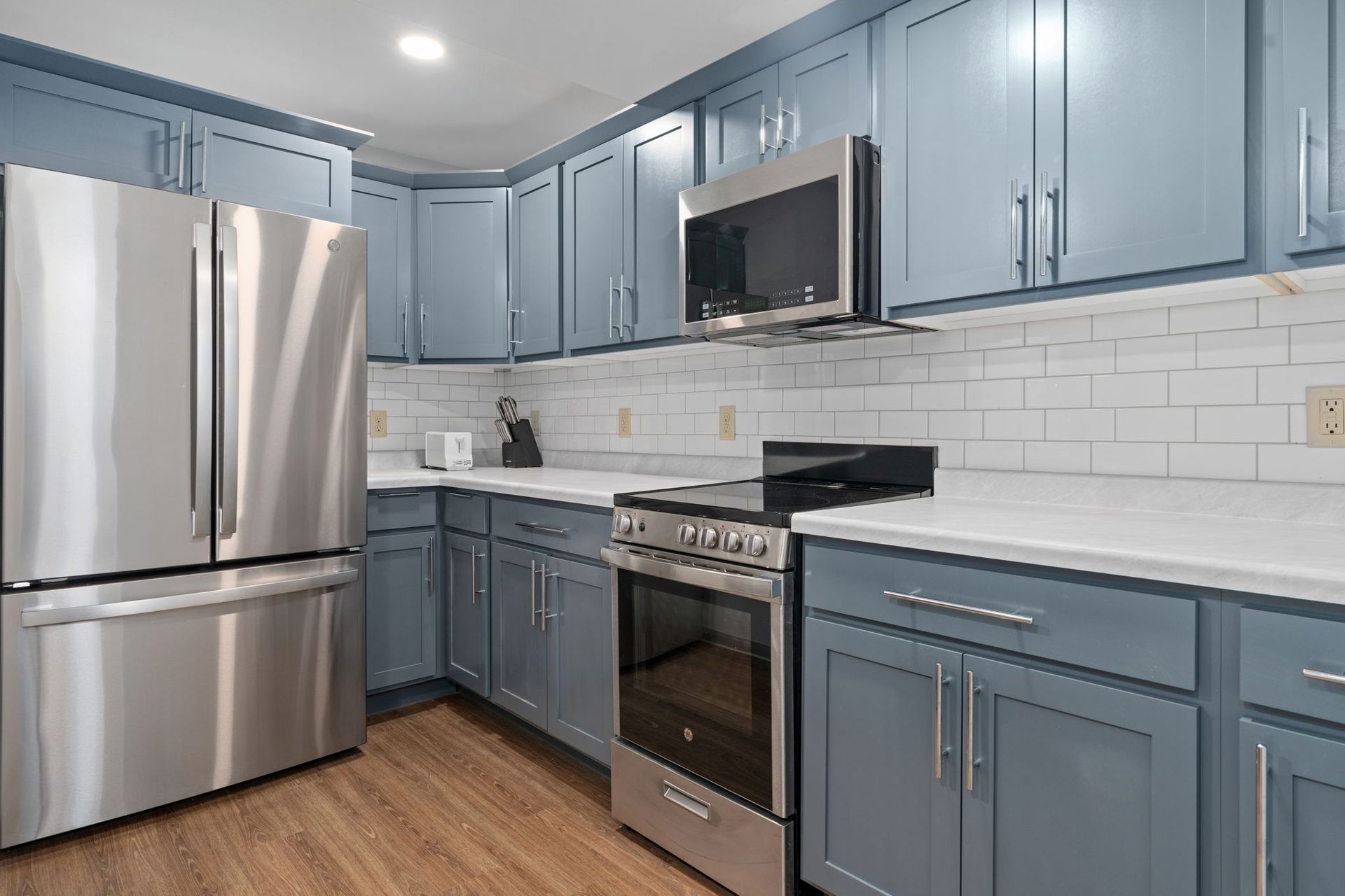 A kitchen with blue cabinets and stainless steel appliances.