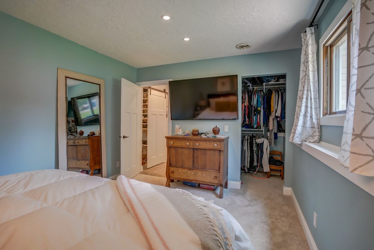 A bedroom with a bed , dresser , television and walk in closet.