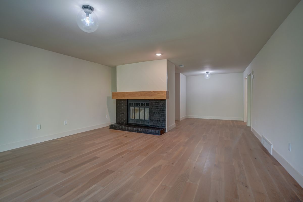 An empty living room with hardwood floors and a fireplace.