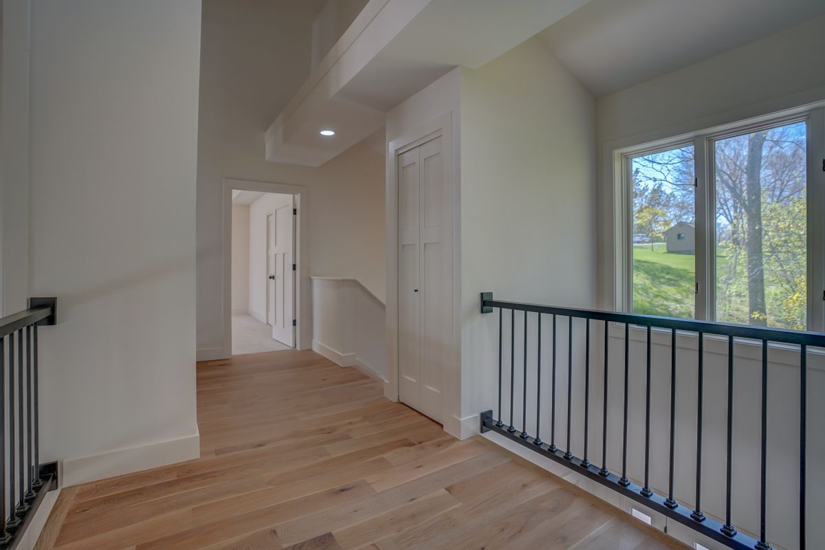 A hallway with a railing and a window in a house.
