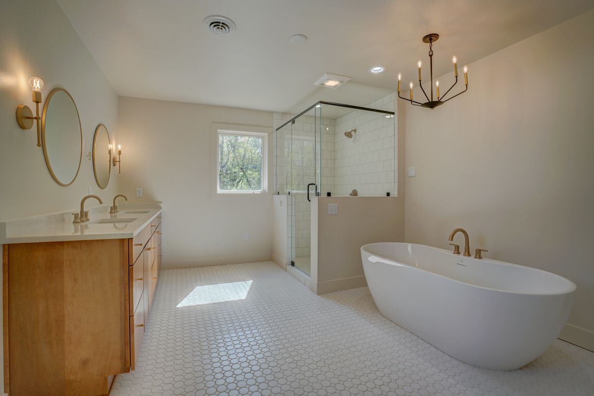 A bathroom with two sinks , a tub , and a walk in shower.