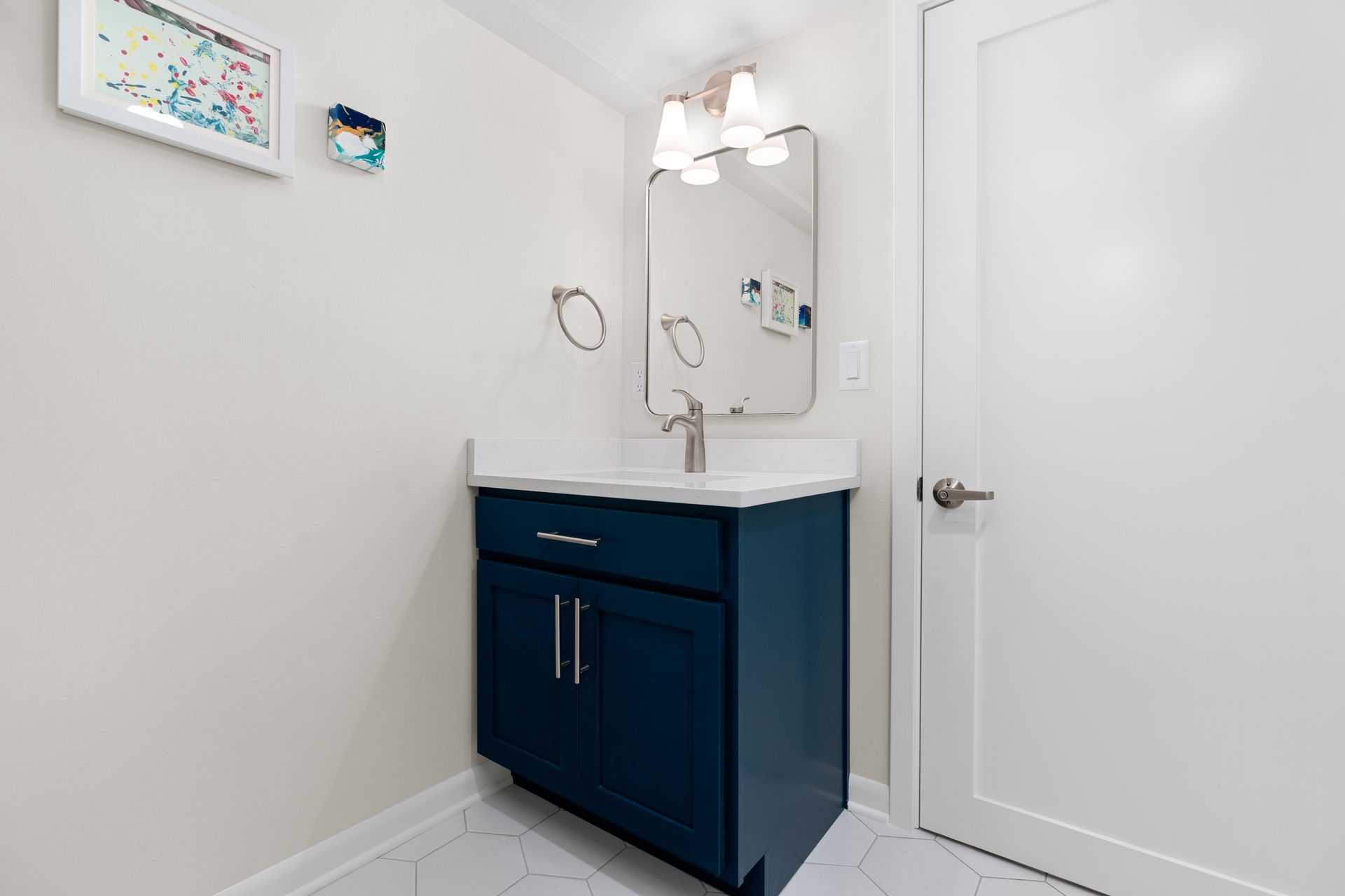 A bathroom with a blue vanity and a mirror.