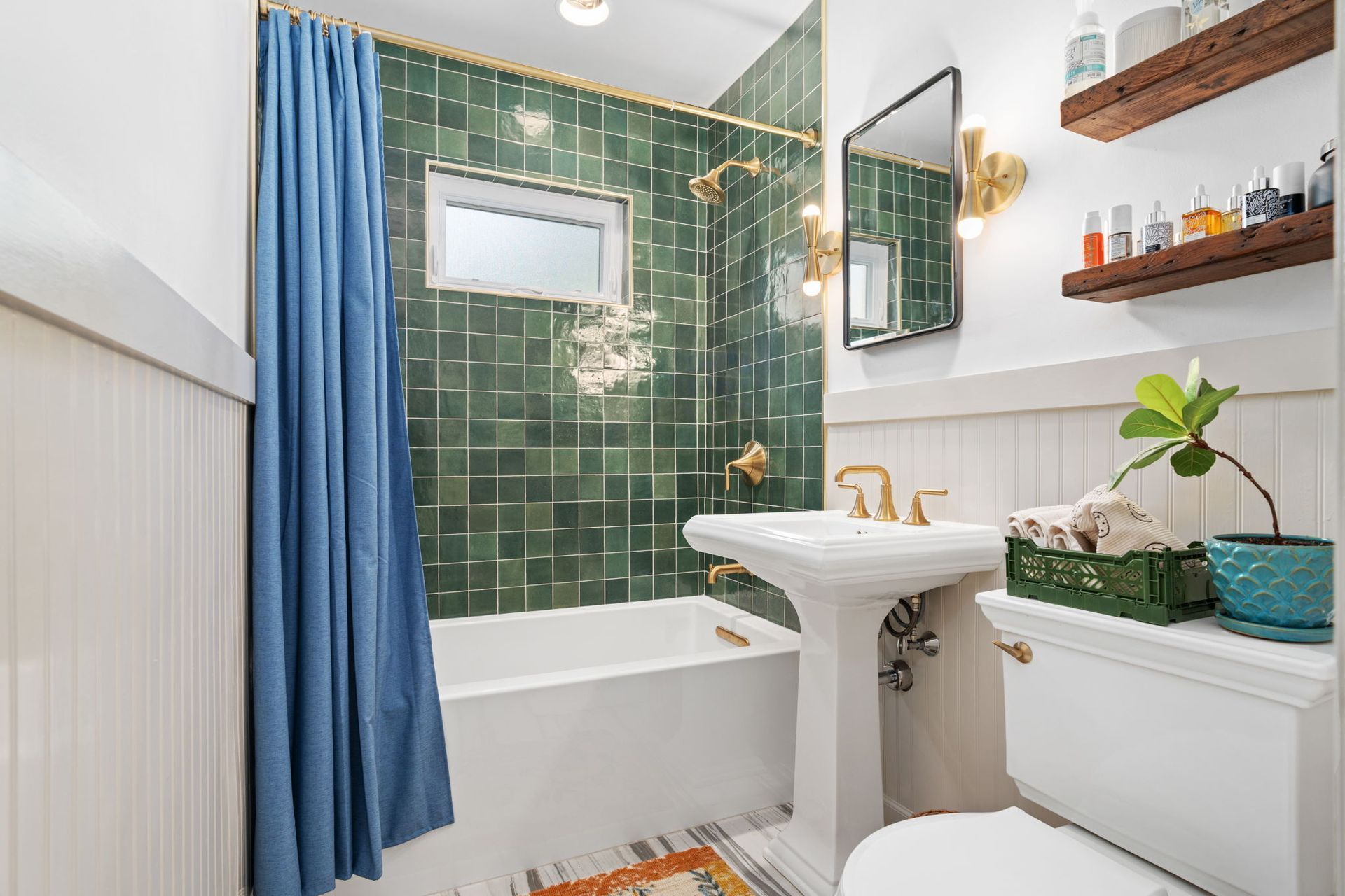 A bathroom with green tiles and a blue shower curtain.