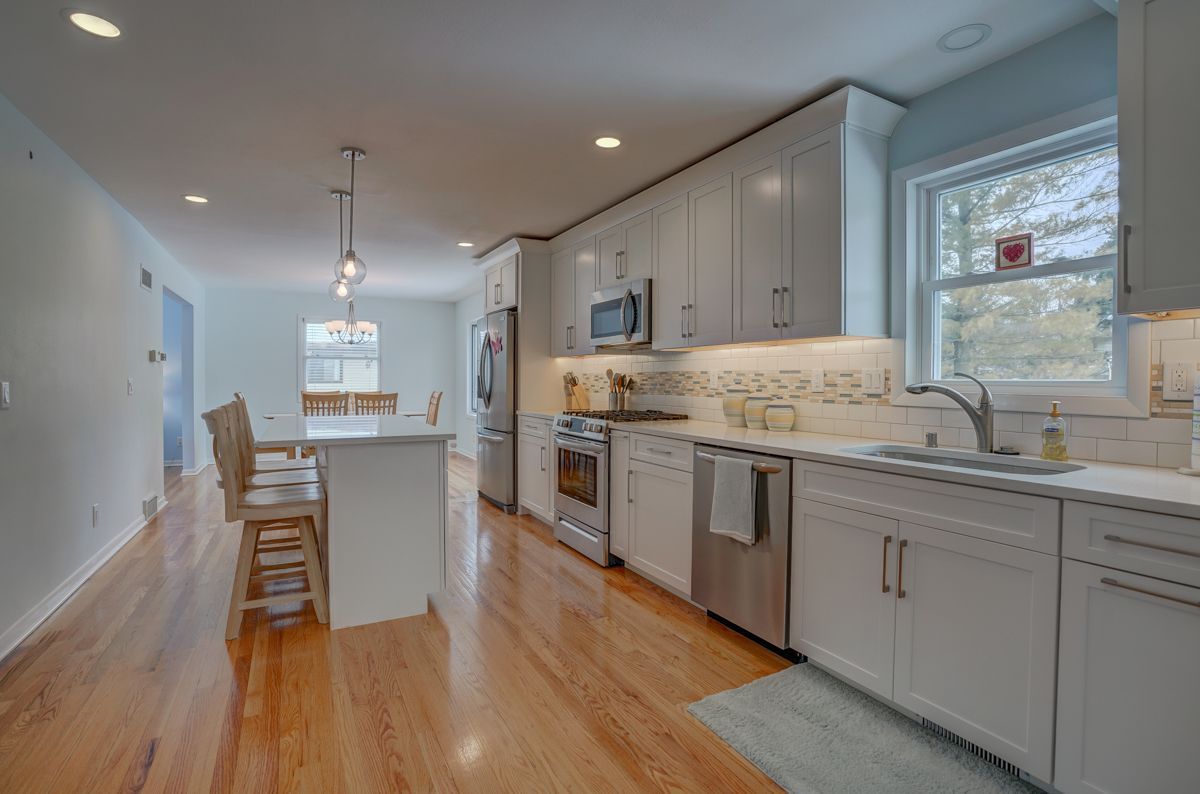 A kitchen with white cabinets and stainless steel appliances and hardwood floors.