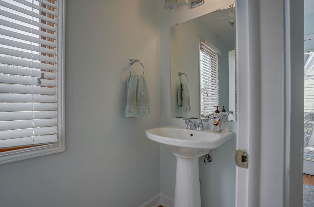 A bathroom with a sink , mirror and blinds.