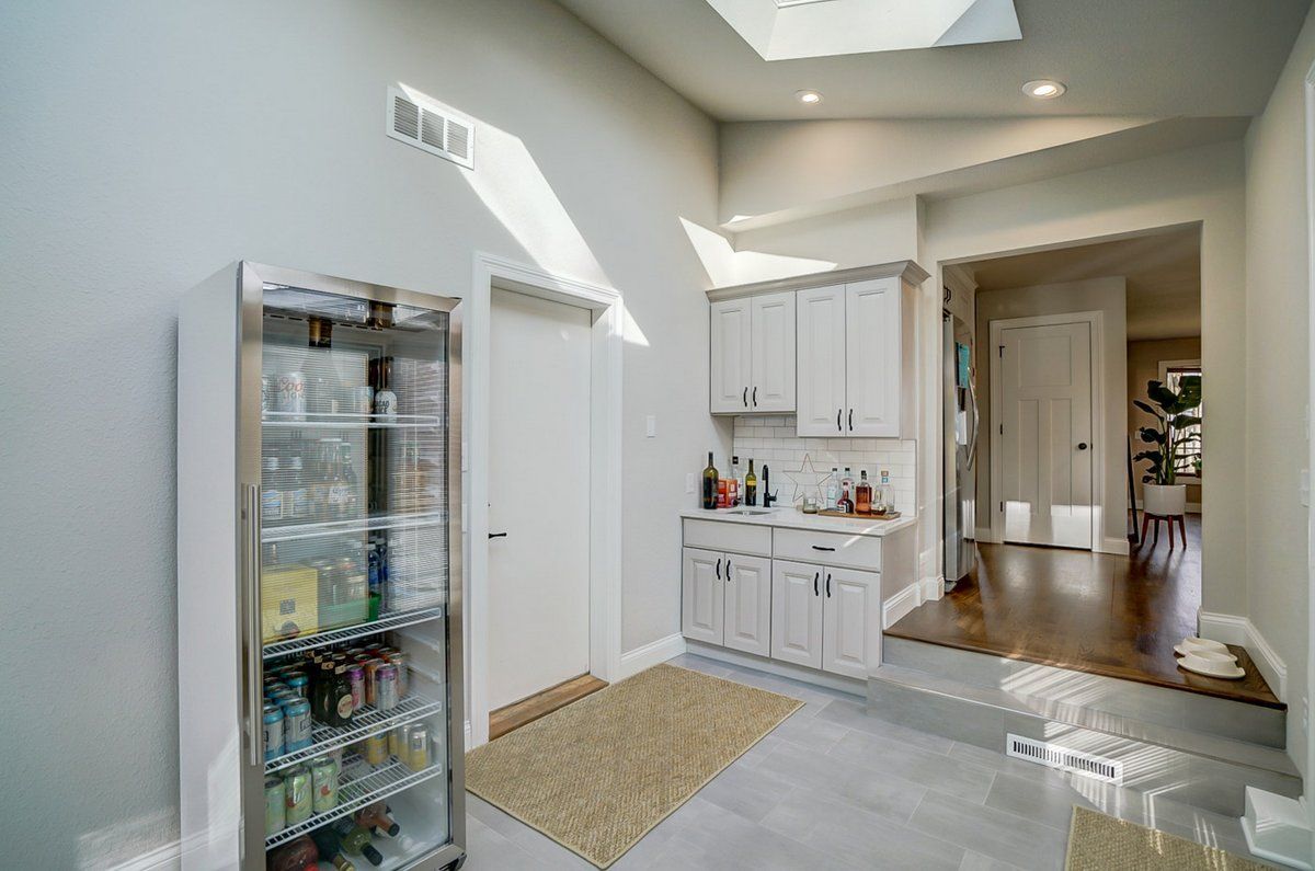 A kitchen with white cabinets , a refrigerator , and a skylight.