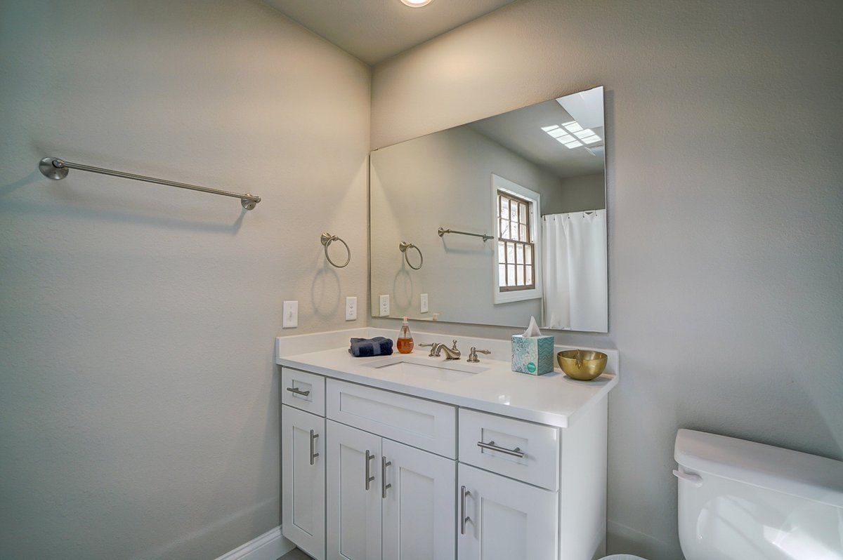 A bathroom with a sink , toilet and mirror.