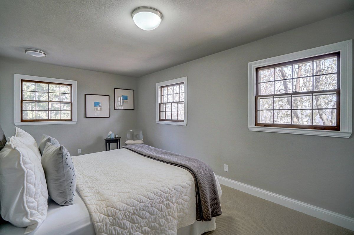 A bedroom with a bed , two windows and a ceiling light.