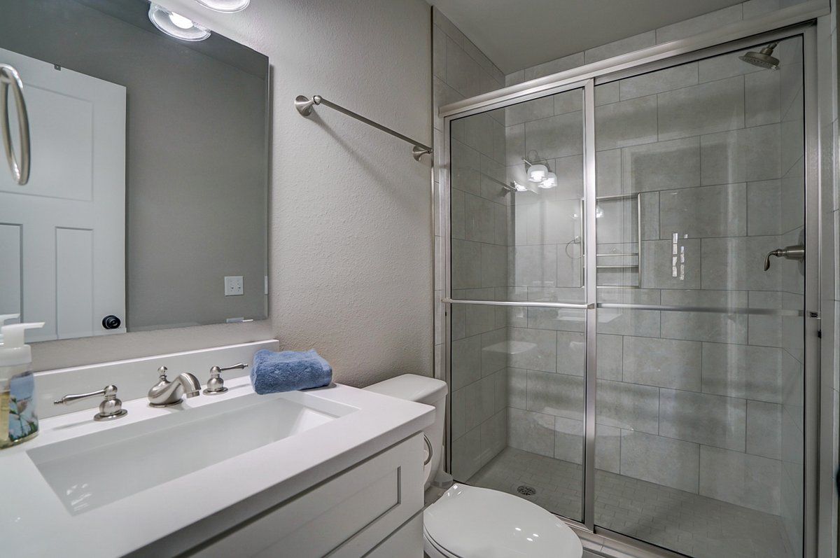 A bathroom with a sink , toilet , shower and mirror.