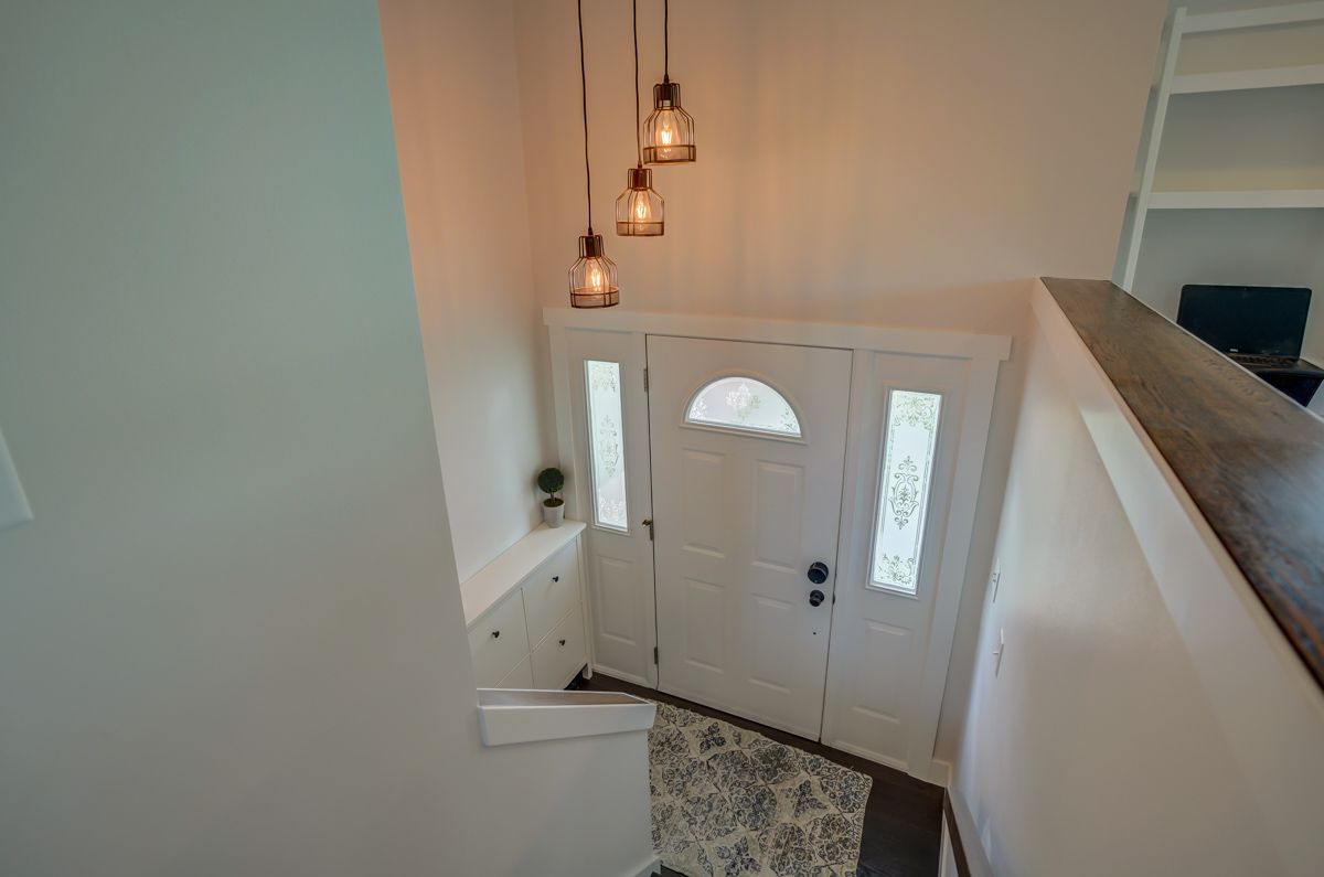 An aerial view of a hallway with a white door and stairs leading to it.