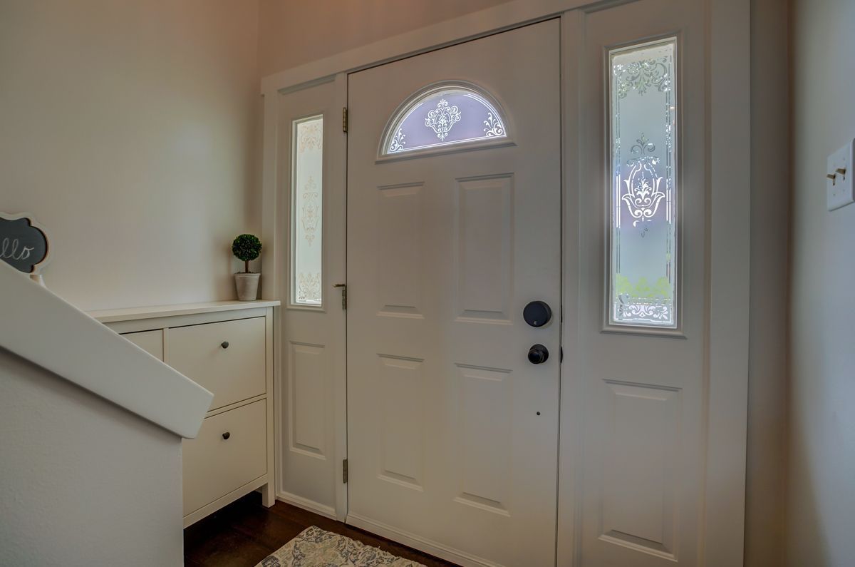 A white door with a stained glass window is in a hallway next to a staircase.