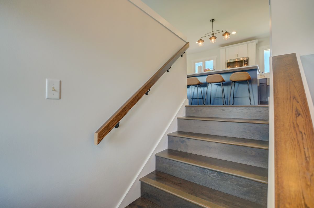 A set of stairs leading up to a kitchen with a wooden railing.