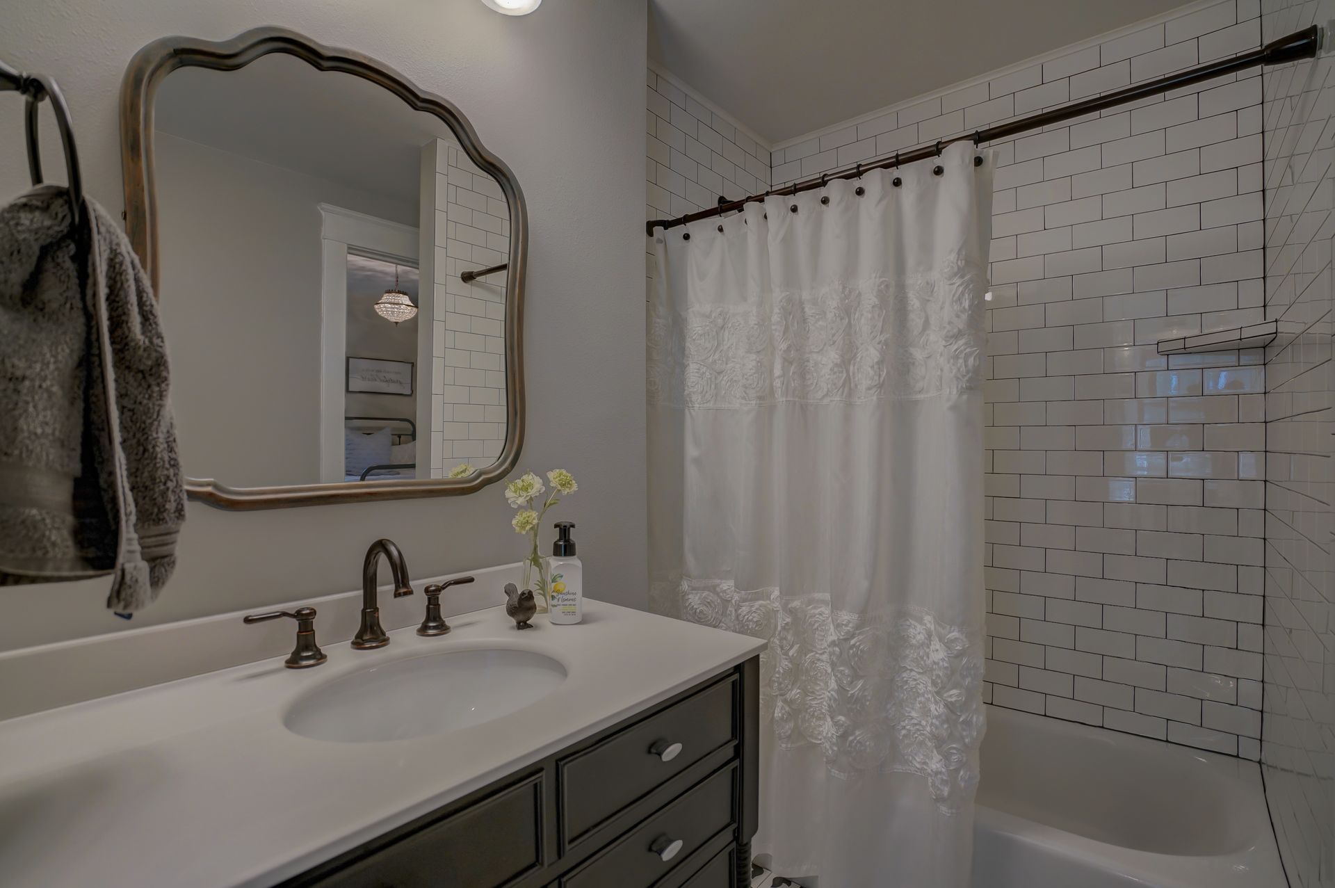 A bathroom with a sink , mirror and shower curtain.