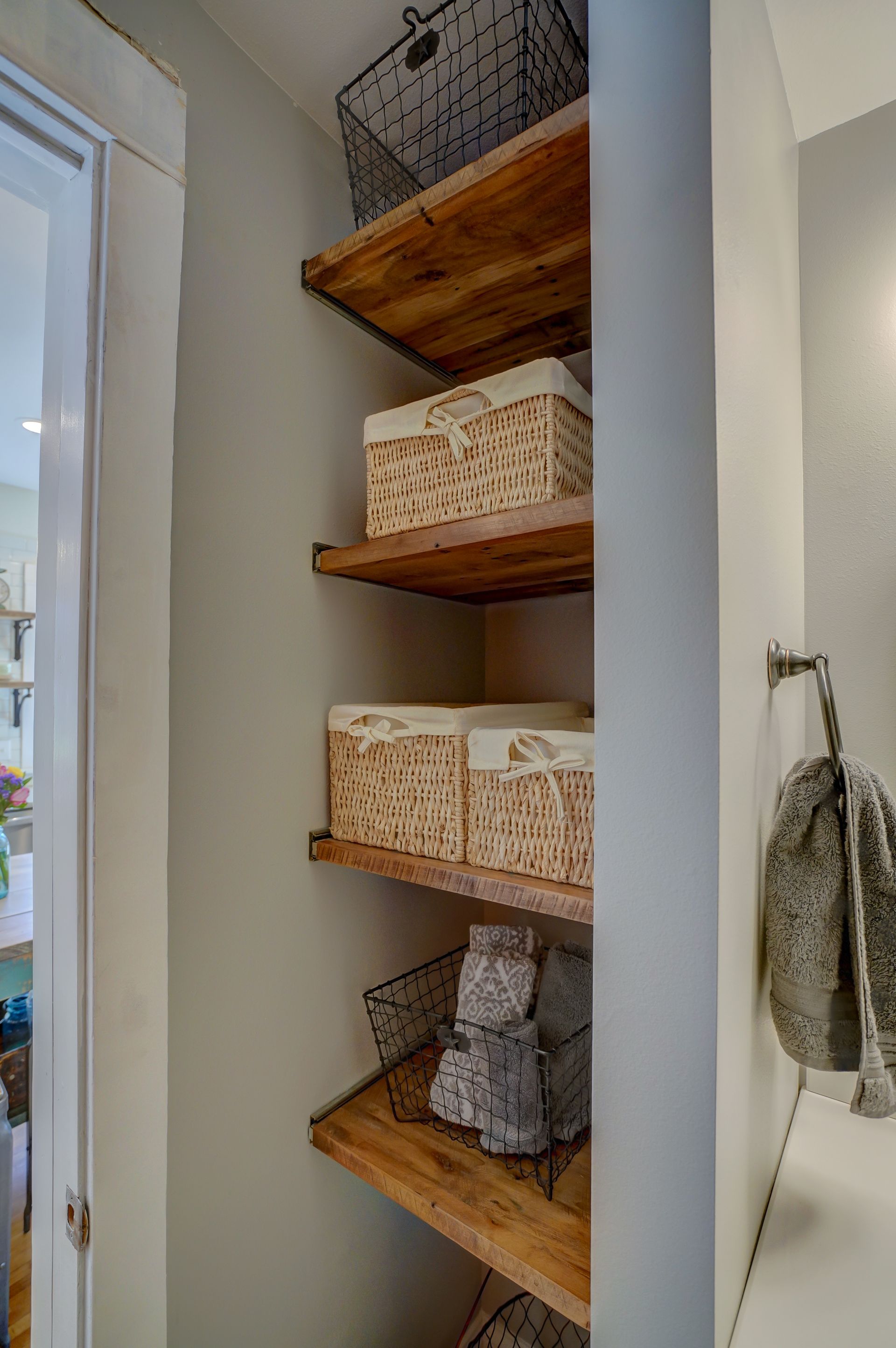 A closet with wooden shelves and baskets in it.