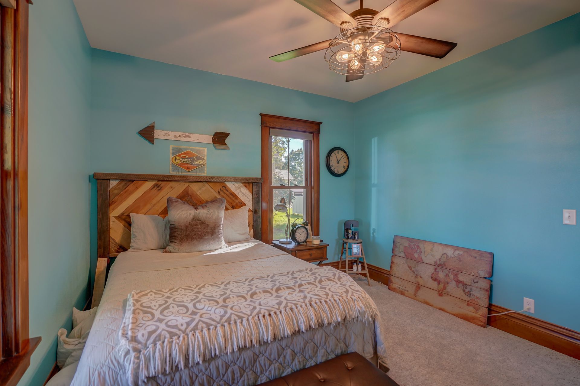 A bedroom with blue walls , a bed , a ceiling fan and a window.