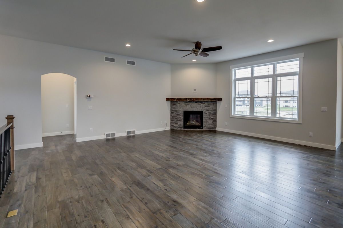 An empty living room with hardwood floors and a fireplace.