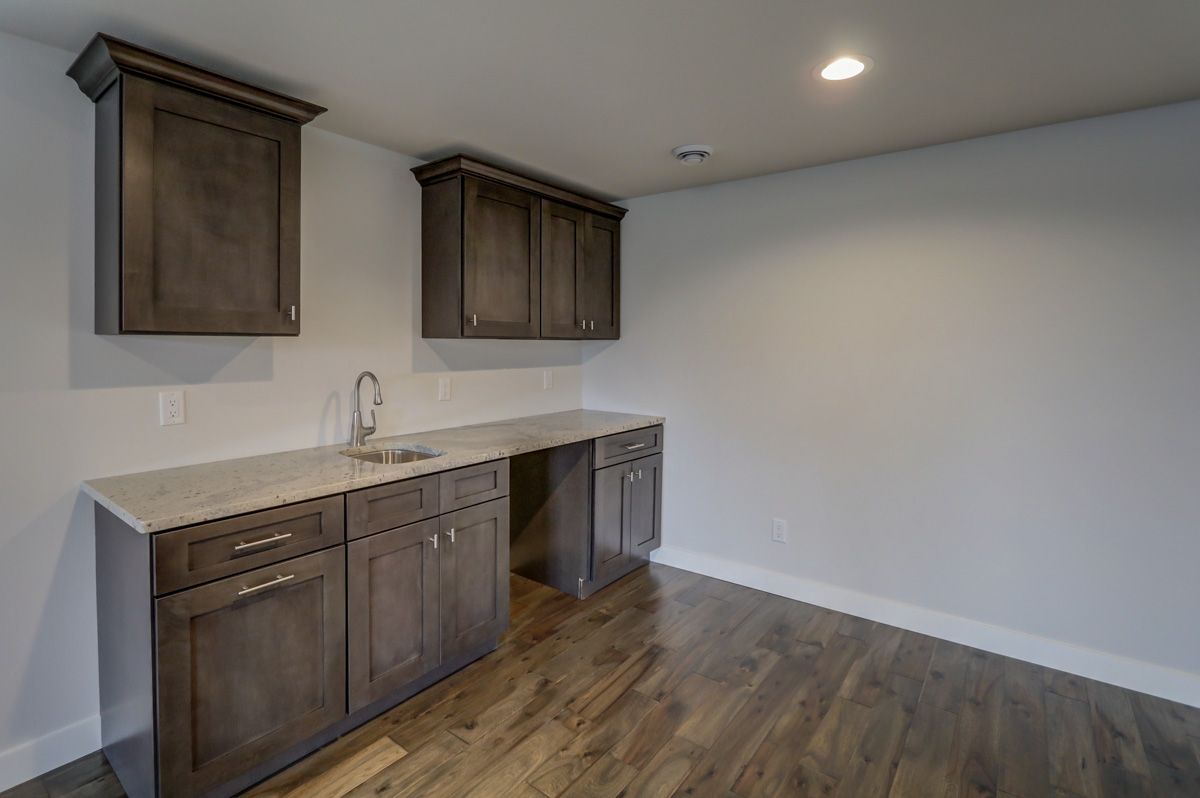 A kitchen with a sink , cabinets , and hardwood floors.