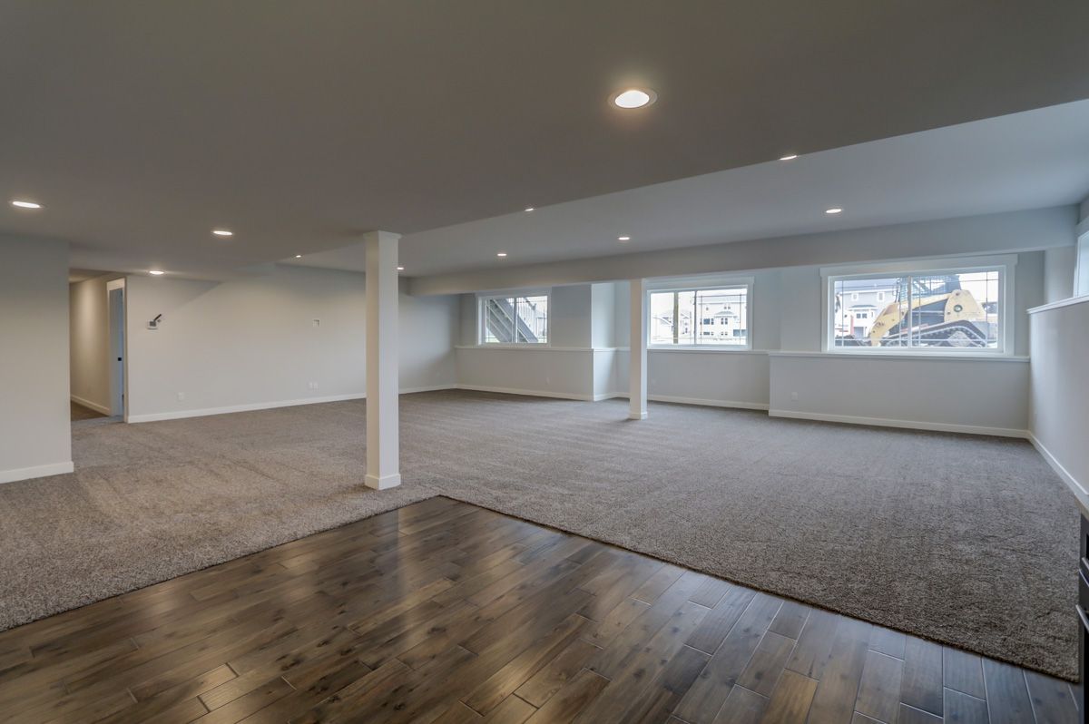 An empty basement with hardwood floors and a lot of windows.