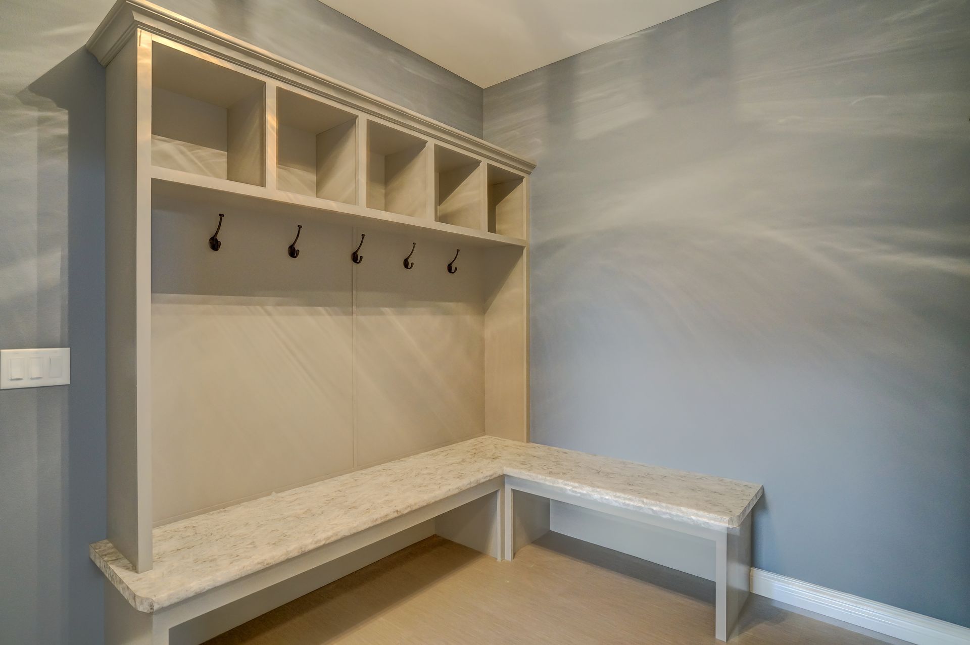 A mud room with a bench and hooks on the wall.