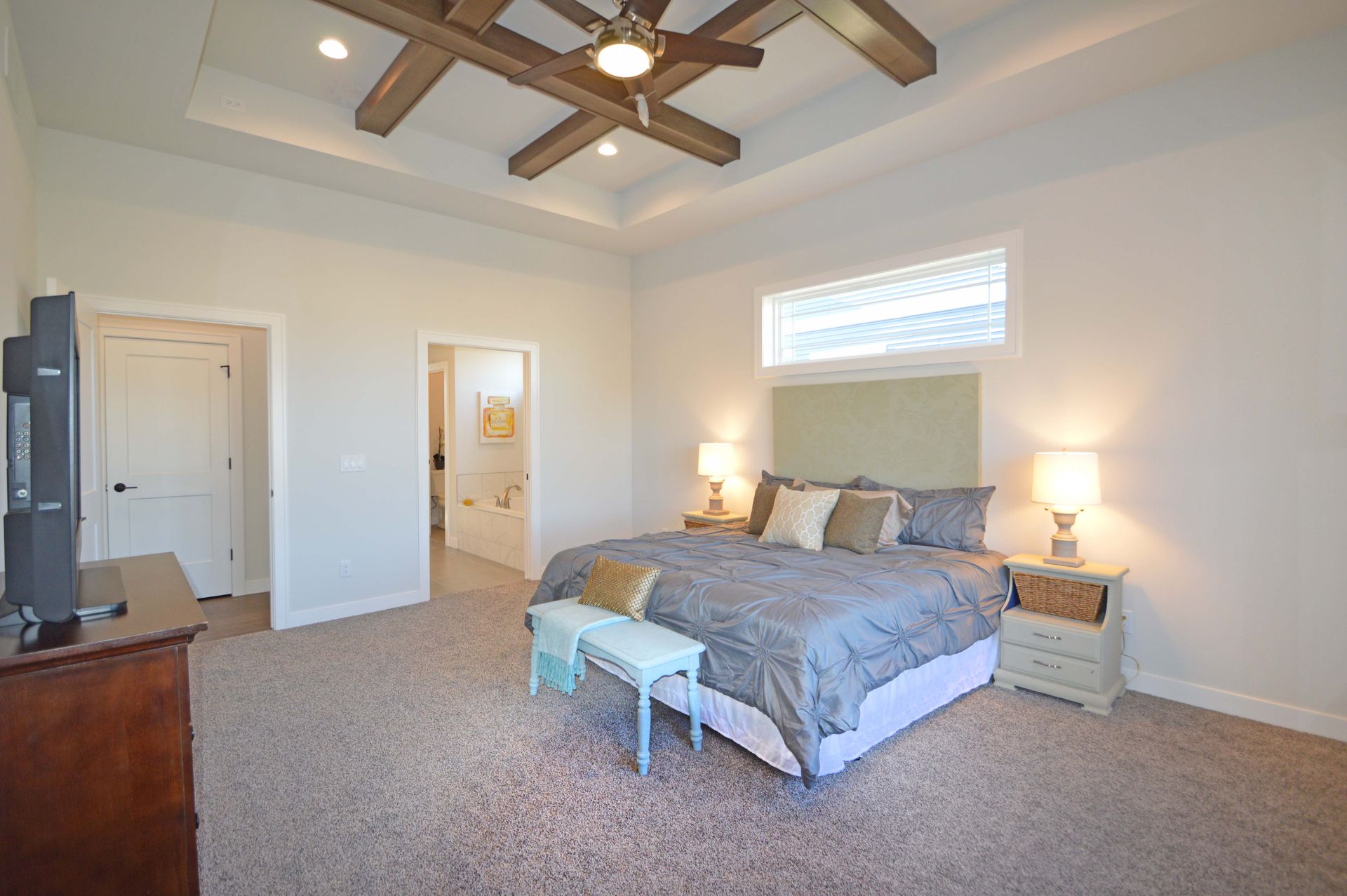 A bedroom with a king size bed , nightstands , a television and a ceiling fan.
