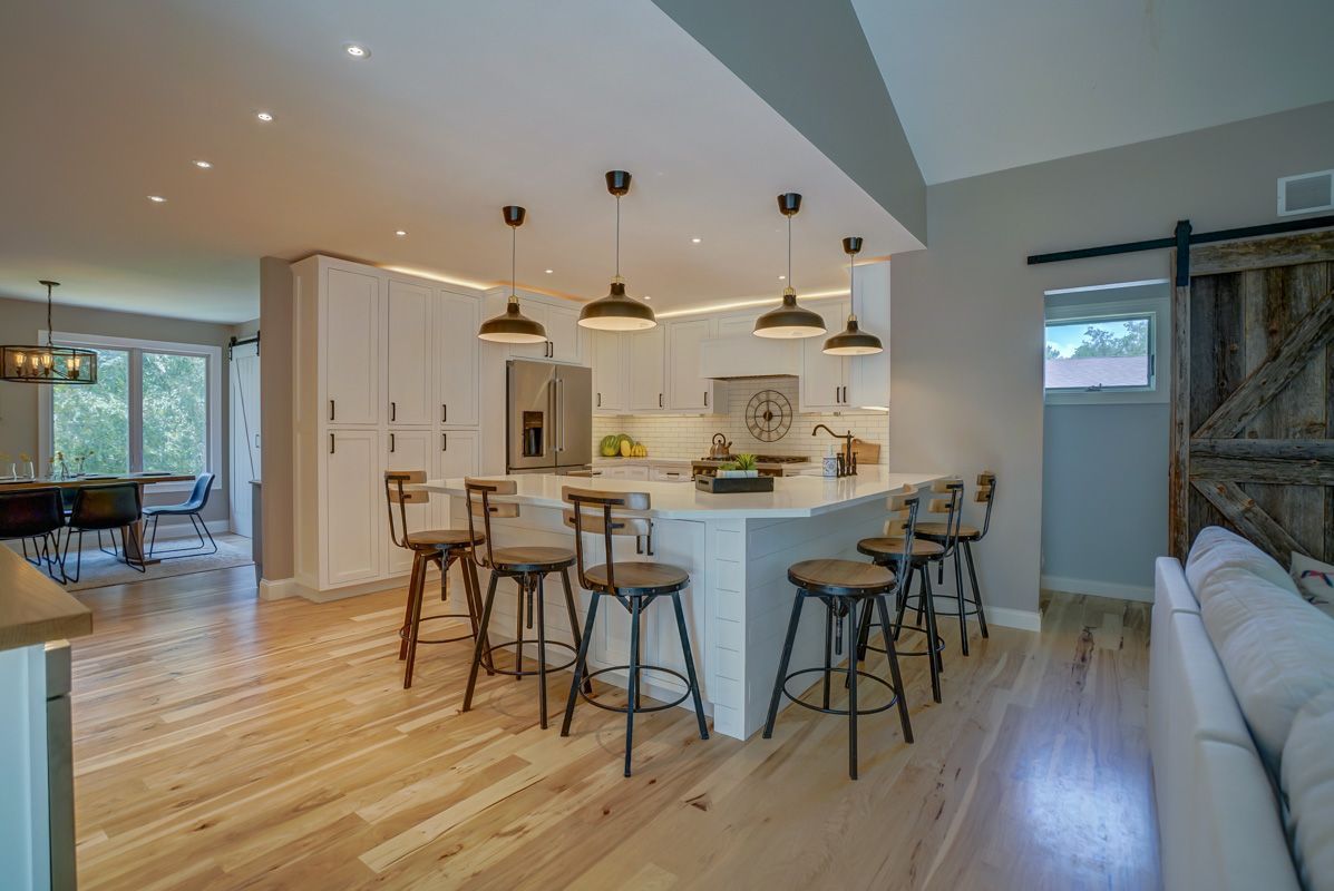 A kitchen with a large island and stools in it.