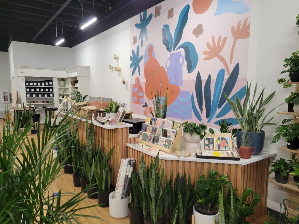 A store filled with lots of potted plants and a mural on the wall.