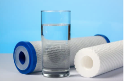 A glass of water is sitting on a table next to two water filters.