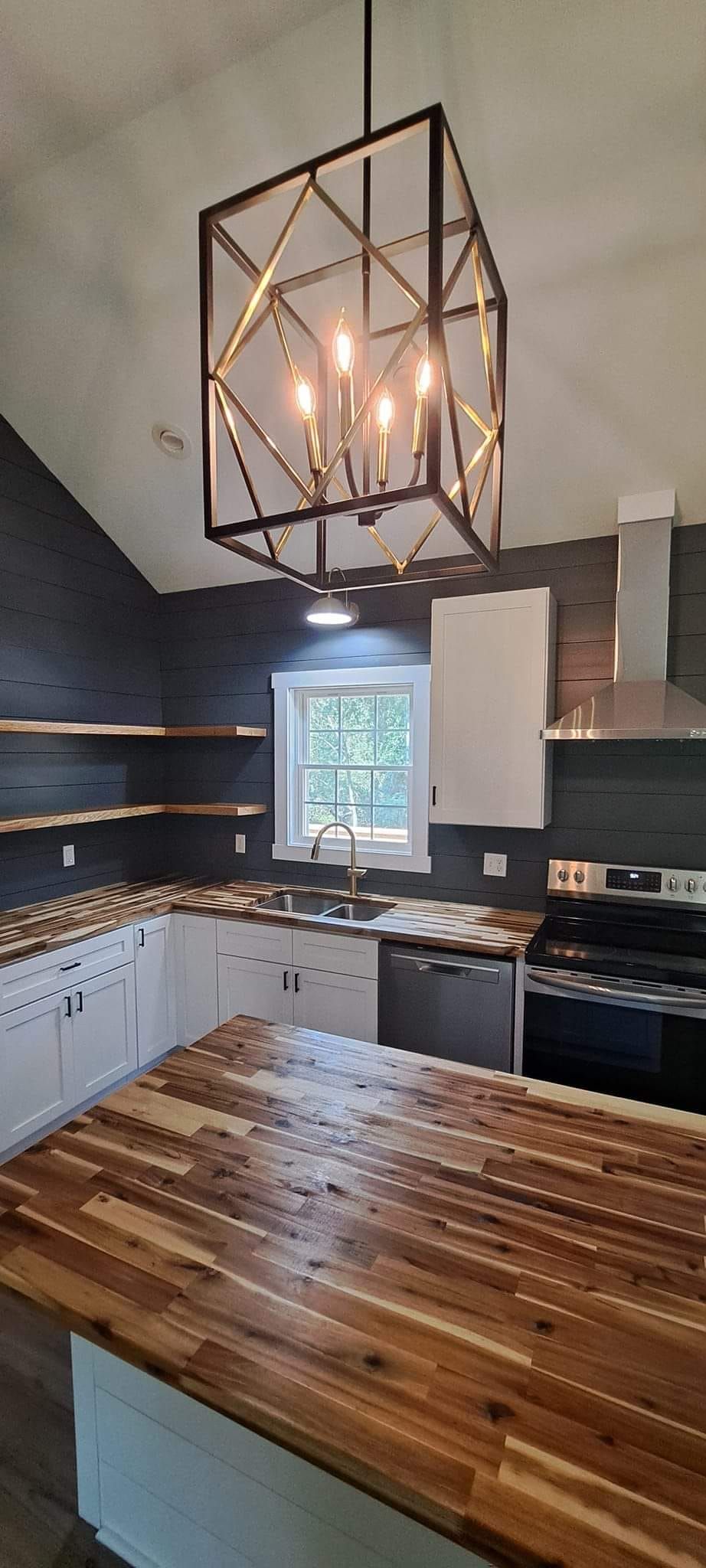 Two air conditioning units sit on a light wood deck next to a white door and gray vertical siding on a house exterior.