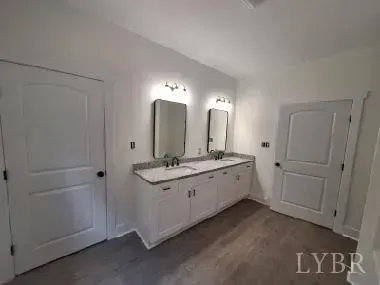 A double-sink bathroom vanity with two mirrors and wall lighting, centered between two white interior doors.