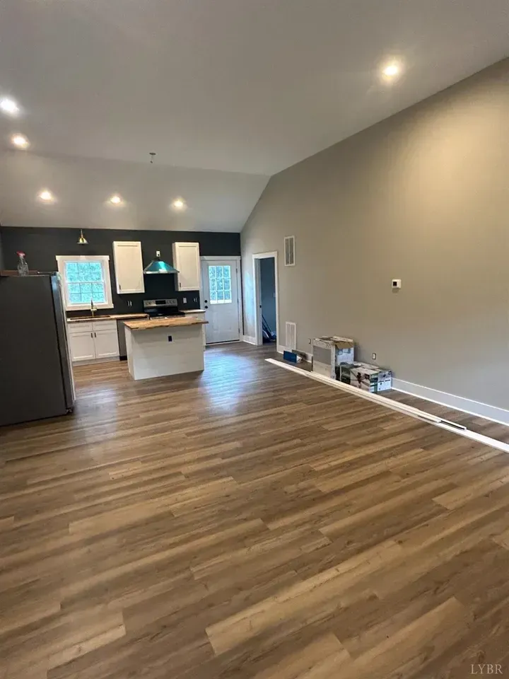 Open-concept kitchen and living area with wood-look flooring, light gray walls, white cabinets, and a kitchen island.