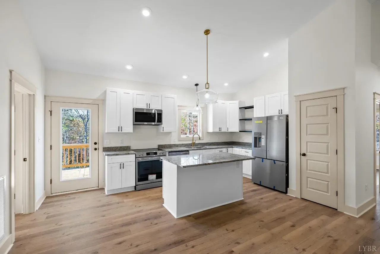 Modern kitchen with white cabinets, stainless steel appliances, a central island, and wood flooring.