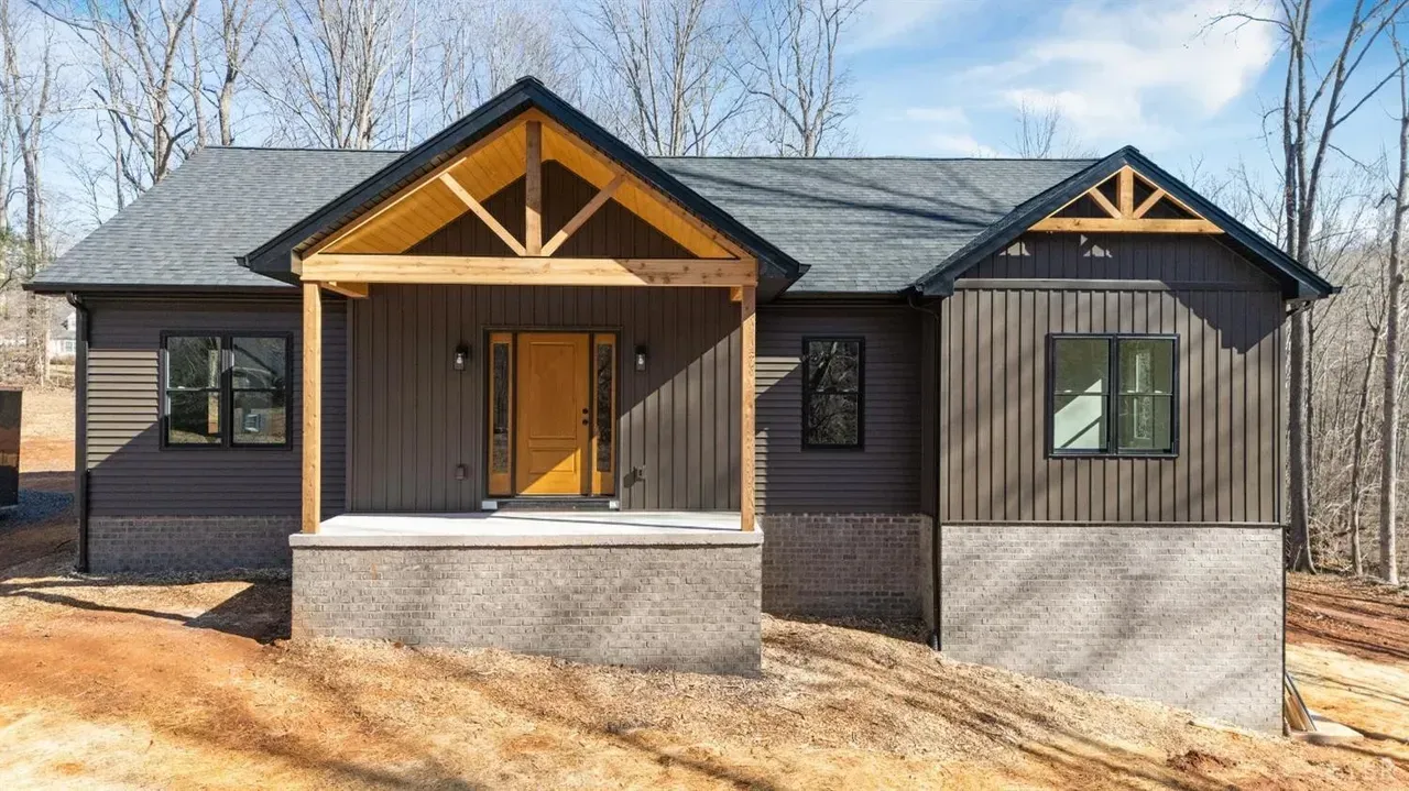 An entryway with wood flooring, white walls, a central wooden front door with side windows, and a closed door on the right.
