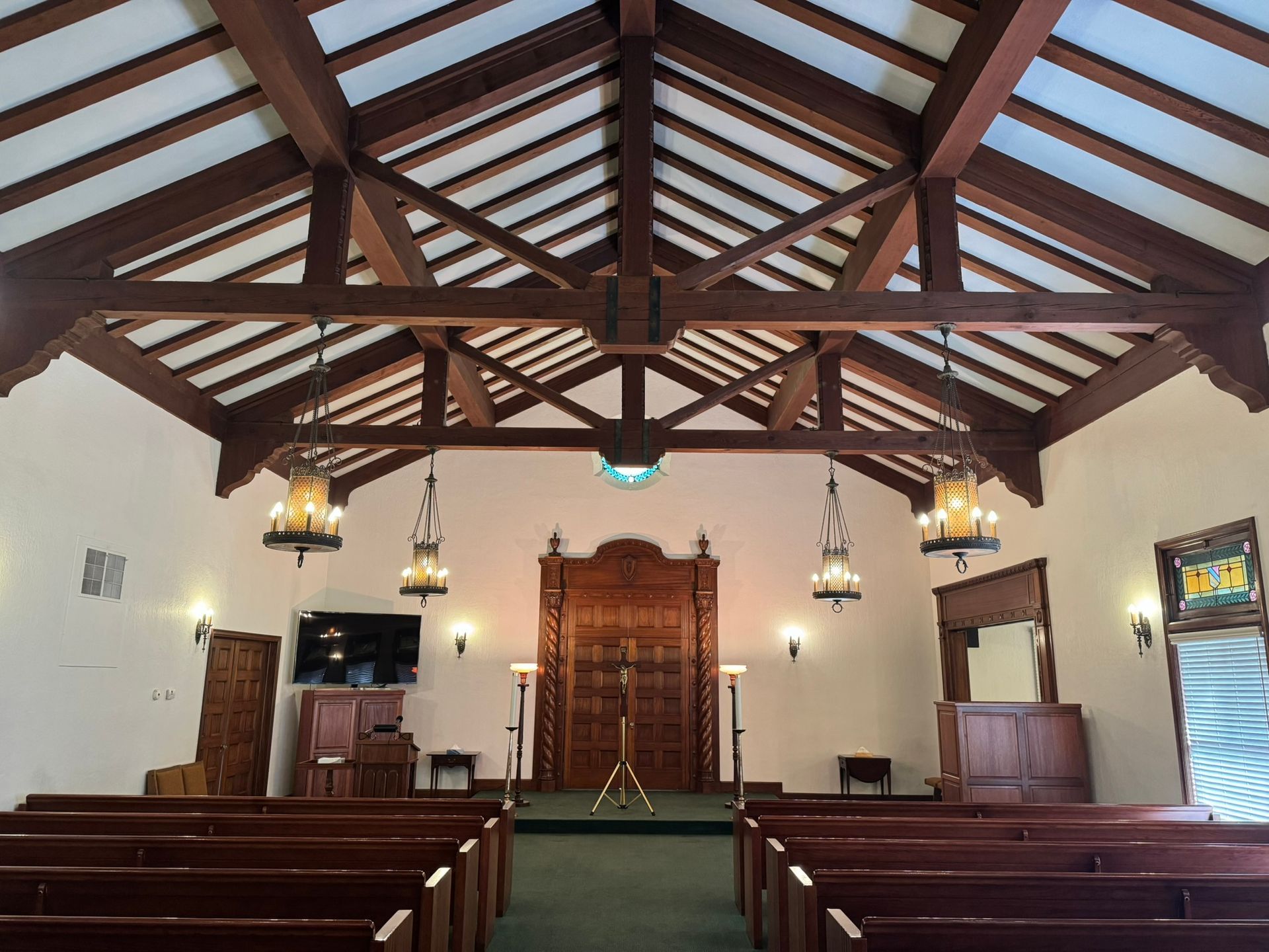 Interior of a chapel with wooden beams, pews, and a Torah ark.