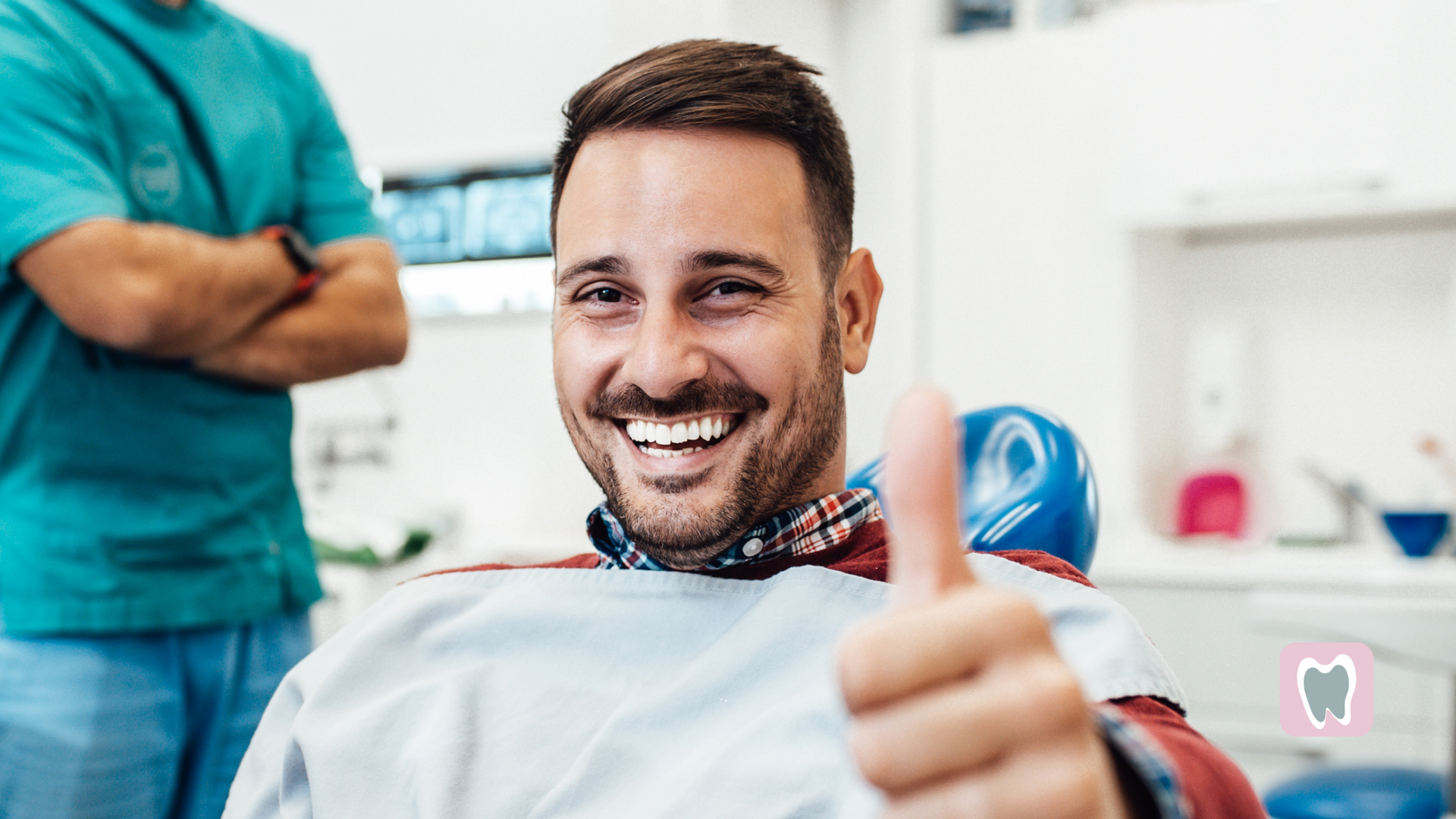 A man is giving a thumbs up while sitting in a dental chair.