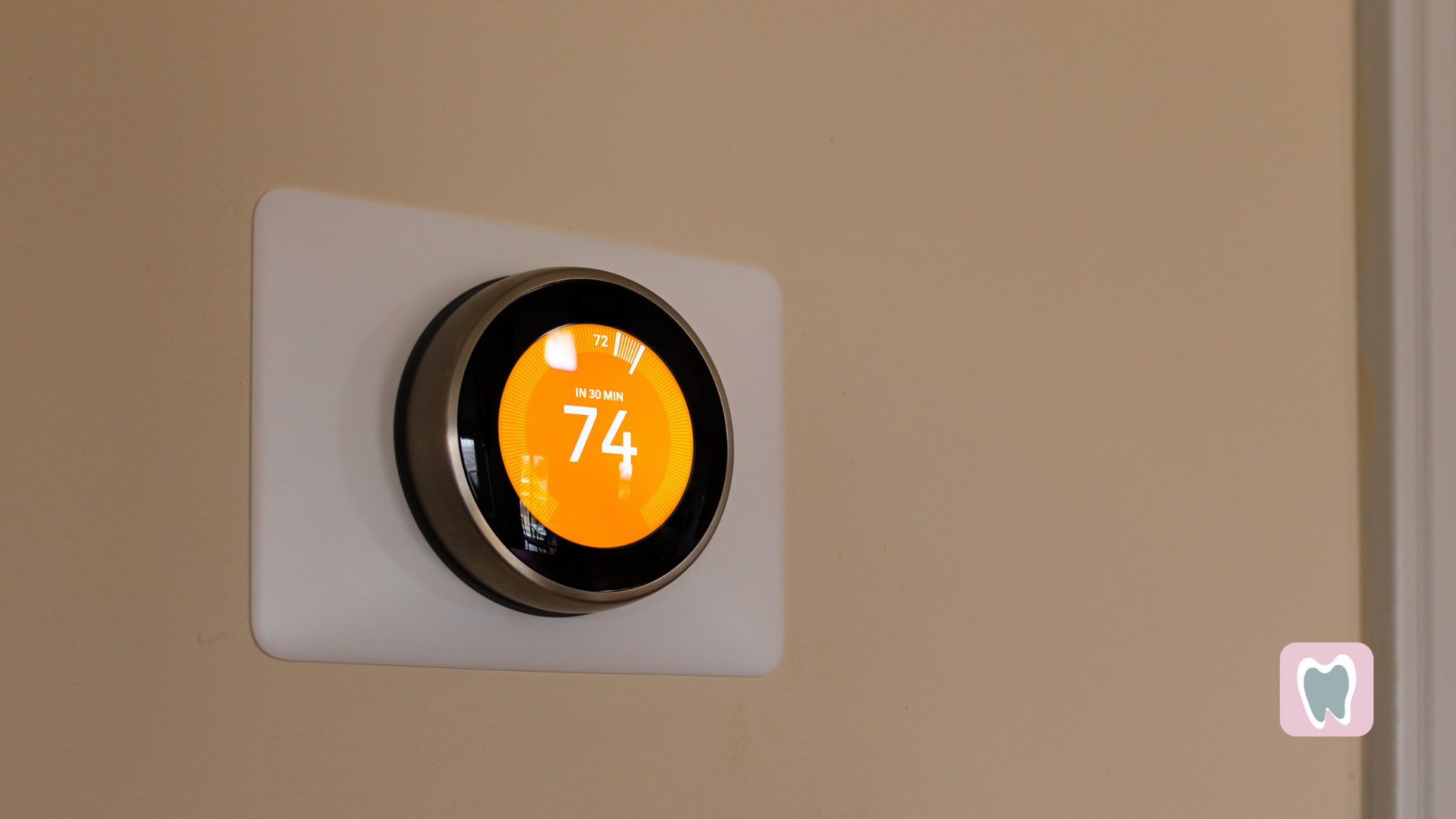 A smart thermostat is hanging on a wall and the temperature is 74 degrees fahrenheit.