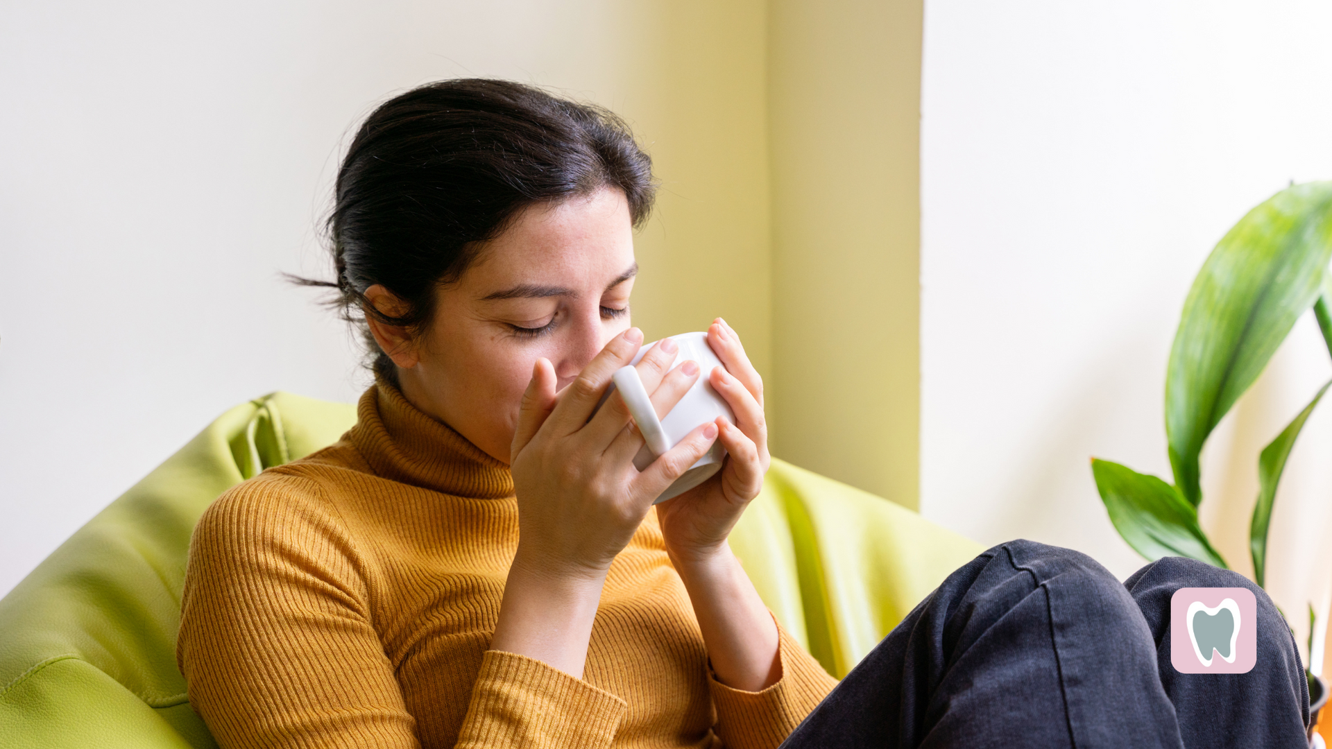 A woman is sitting on a bean bag chair drinking from a cup.