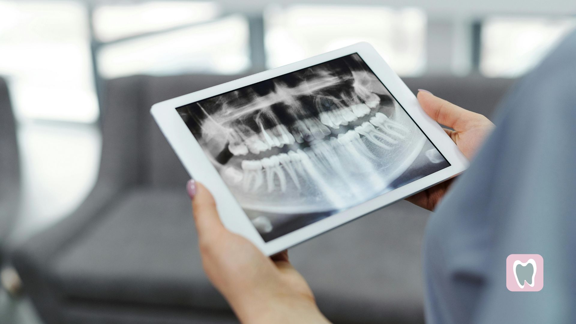 A woman is holding a tablet with an x-ray of her teeth on it.