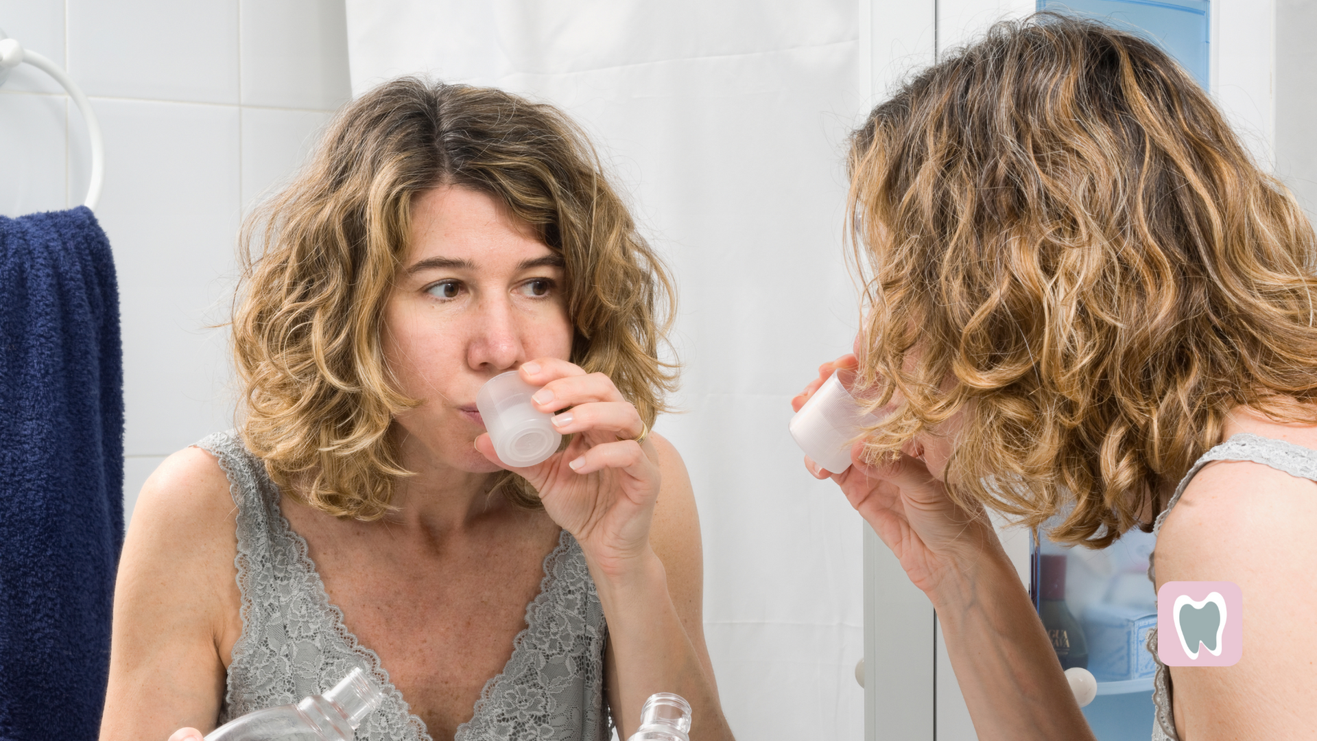 A woman is brushing her teeth in front of a mirror in a bathroom.