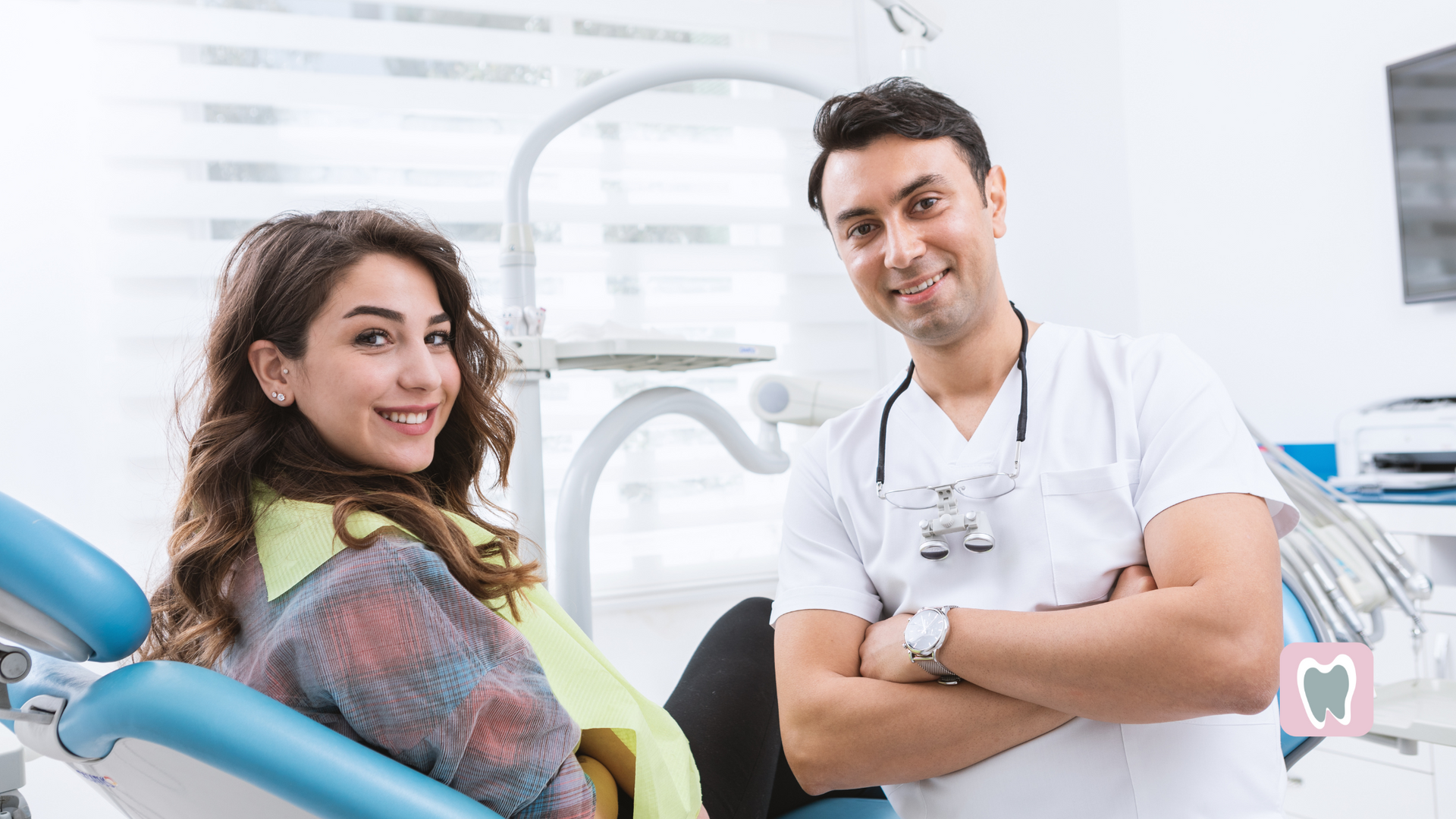 A woman is sitting in a dental chair next to a dentist.